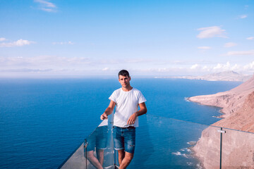 Tourist on a viewpoint against the ocean and volcanic cliffs