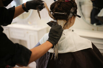 女性の髪のカラーリングをする男性美容師