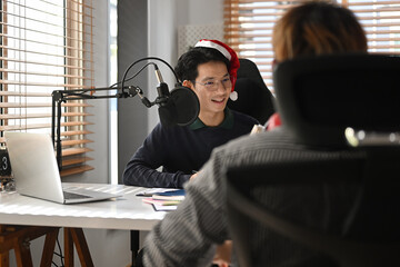 The Asian radio host man moderating a live show for radio with guest speaker on the Christmas Day.