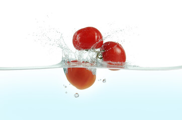 Three tomatoes splashing in water.