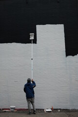 a man painting the wall outside