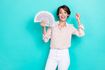 Photo of hooray brown hairdo young lady hold money wear white shirt pants isolated on teal color background