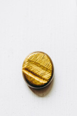 Galet pierre roulée polie oeil de tigre sur un fond blanc avec espace vide - Minéral naturel