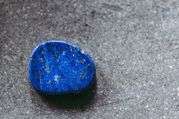 Galet pierre roul&eacute;e polie lapis-lazuli sur un fond noir avec espace vide - Min&eacute;ral naturel