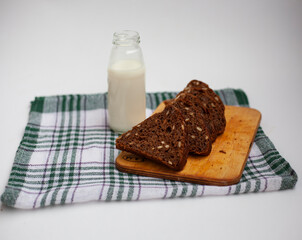 basket of cereal rolls, bagels and slices of rye bread, next to a bottle of milk