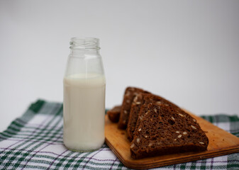 Slices of rye bread next to a bottle of milk on the kitchen table.
