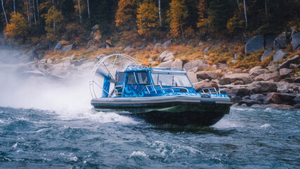 the air boat in passes the river threshold. The boat is on the screw. Yellow autumn with blue water