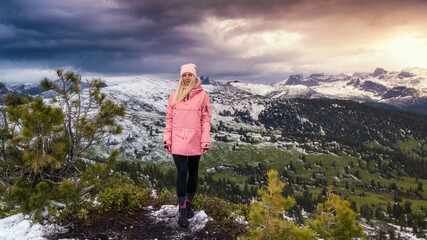 a woman on top of a mountain at sunset, in the first snow.
