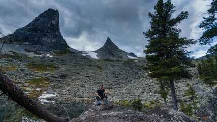 Fototapeta na wymiar a man in the mountains is sitting on a rock. against the background of a parabolic mountain