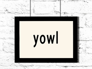 Black frame hanging on white brick wall with inscription yowl
