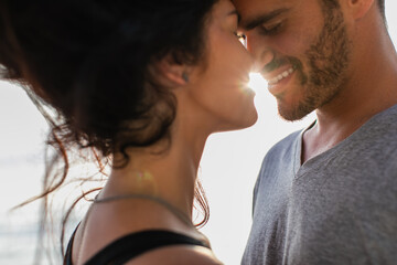 portrait of bearded man and brunette woman with closed eyes smiling outside.