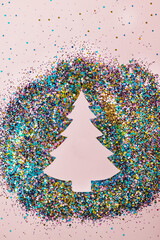 Negative space Christmas tree concept made with colorful sequin pattern. Creative New Year party layout. Winter flat lay with copy space.