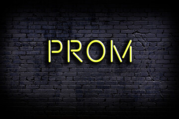 Neon sign. Word prom against brick wall. Night view