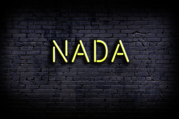 Neon sign. Word nada against brick wall. Night view