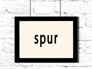 Black frame hanging on white brick wall with inscription spur © iushakovsky