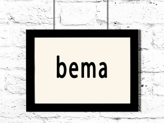 Black frame hanging on white brick wall with inscription bema