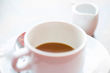Defocused view of white cup of hot coffee