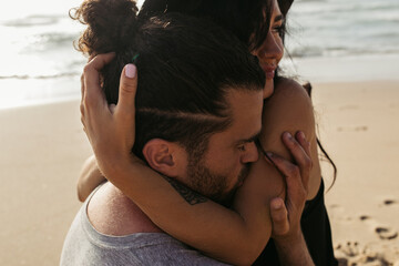bearded man kissing hand on happy woman with tattoo on beach.