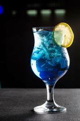 blue alcoholic drink in glass on black table