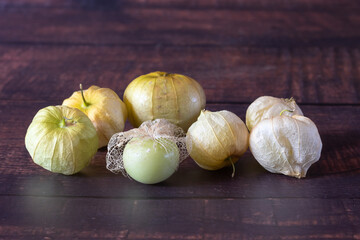 A tomatillo with only the skeleton of its husk and several more still inside an intact husk.