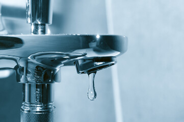 Chrome tap with falling water drop close up