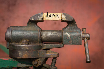 Vice grip tool squeezing a plank with the word damn - obrazy, fototapety, plakaty