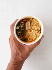 Close-up cooked instant noodles in hand.