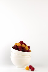 The purity of white bowls overflowing with colorful raspberries captures a sense of freshness and simplicity, perfect for a healthy theme