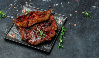 Roasted pork steaks, cutlets with rosemary and spices on a dark background. Long banner format. top view