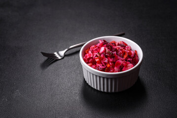 Traditional ukrainian beetroot salad vinaigrette on a white plate on a black concrete or slate background