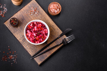 Traditional ukrainian beetroot salad vinaigrette on a white plate on a black concrete or slate background
