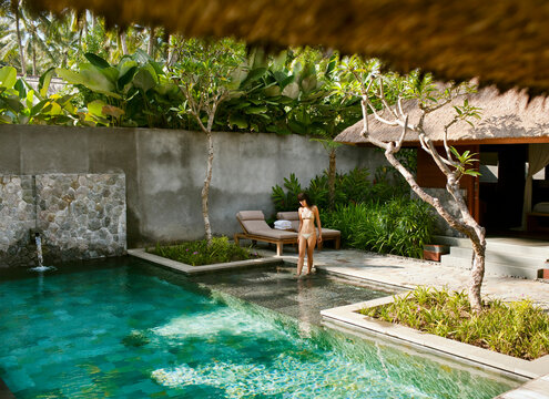 Woman entering pool at a private hotel villa, Ubud, Bali, Indonesia.
