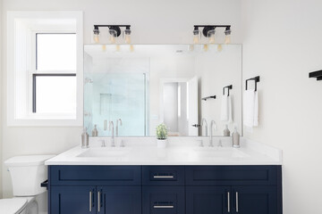A beautiful bathroom with a blue vanity cabinet, white marble countertop, and a view to the marble...