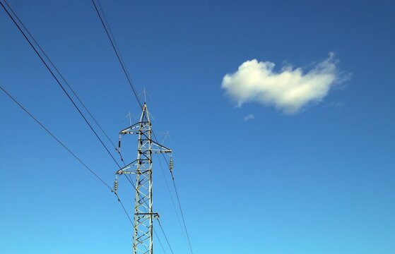 Torre de alta tensión para la conducción de electricidad. Fotografía tomada a mediodía con un cielo azul y una nube solitaria en Toledo, España.