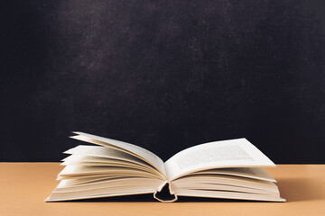 Minimal reading concept made with open book on textured black and brown background. Retro aesthetic.