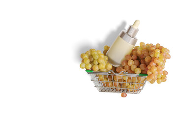 Empty cosmetic package, bottle with bunches of grapes in a shopping cart. The concept of natural cosmetics.