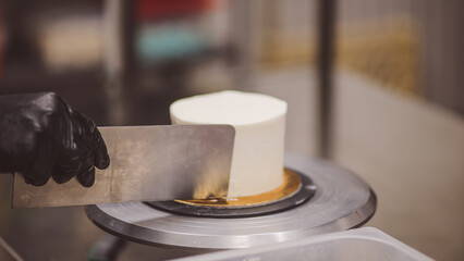 chef cake smoothing a frosted cake with buttercream with spatula and utensils