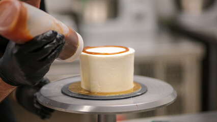 chef designer squeezing bottle with salty caramel filling topping frosted cake