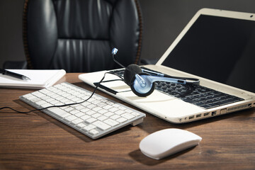 Customer service headset, computer keyboard and business objects on the table.