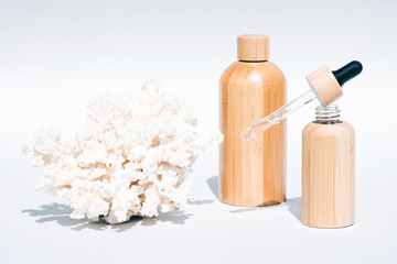 Cosmetic self-care products with natural Dead Sea minerals in refillable wooden bottles against white background with sea corals. Algae oil or sea minerals based beauty products for skin care