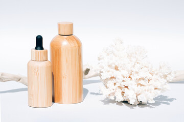 Algae oil or sea minerals based beauty products for skin care. Cosmetic self-care products with natural Dead Sea minerals in refillable wooden bottles against white background with sea corals