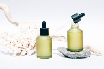 Cosmetic oil with natural Dead Sea minerals in green matte dropper bottles against white background with sea corals - algae oil or sea minerals based cosmetics products for skin care