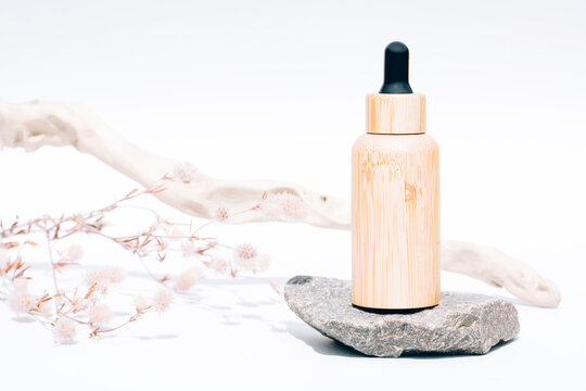 Refillable bamboo dropper bottle with organic cosmetic liquid, herbal oil or face serum against white background. Natural skin care products. Mockup image