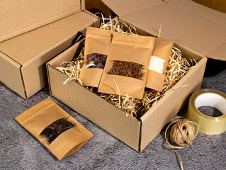 Brown kraft paper doypack bags with groceries on a cardboard box. Packaging for foods and goods...