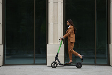 Businesswoman riding electric kick scooter on city street