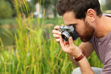 Man with camera taking photo outdoors, space for text. Interesting hobby