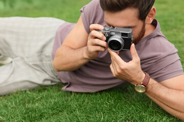 Man with camera taking photo on green grass. Interesting hobby