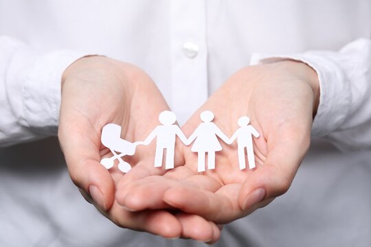 Woman holding paper family figures, closeup. Insurance concept