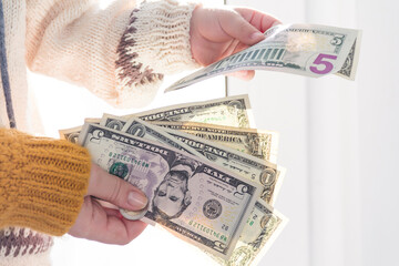 Women's hands and children's hands in a yellow sweater hold small dollar bills.