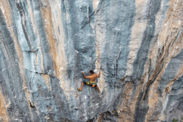 Fototapeta premium Extreme sport, strong man, rock climber climbs a difficult route.